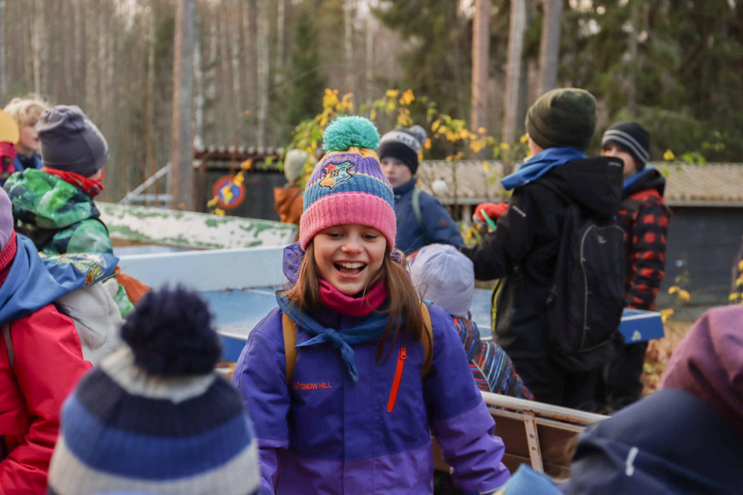 Tre barn och en vuxen scout står uppe å ett fjäll i blåsten och fladdrar med pride flaggor