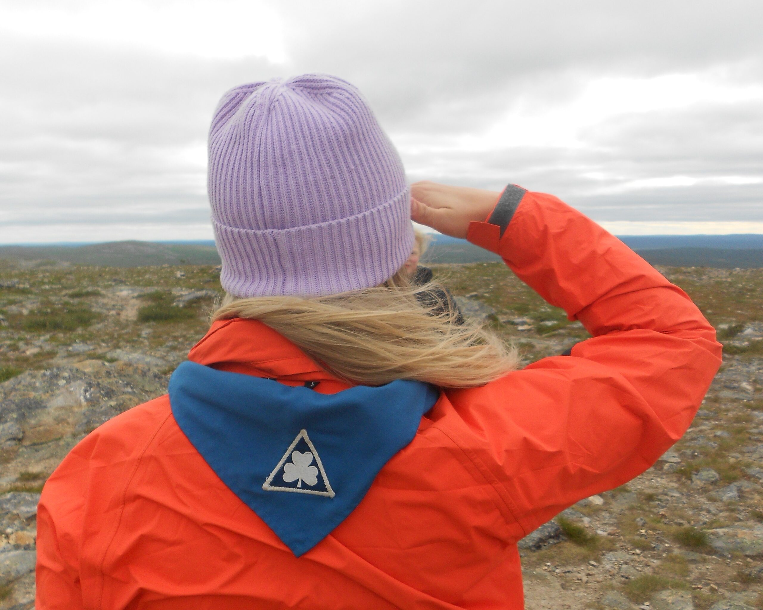 En scout står uppe på ett fjäll i Lappland med scouthalsduken på