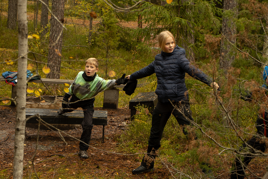 Två barn leker tillsammans ute i skogen 